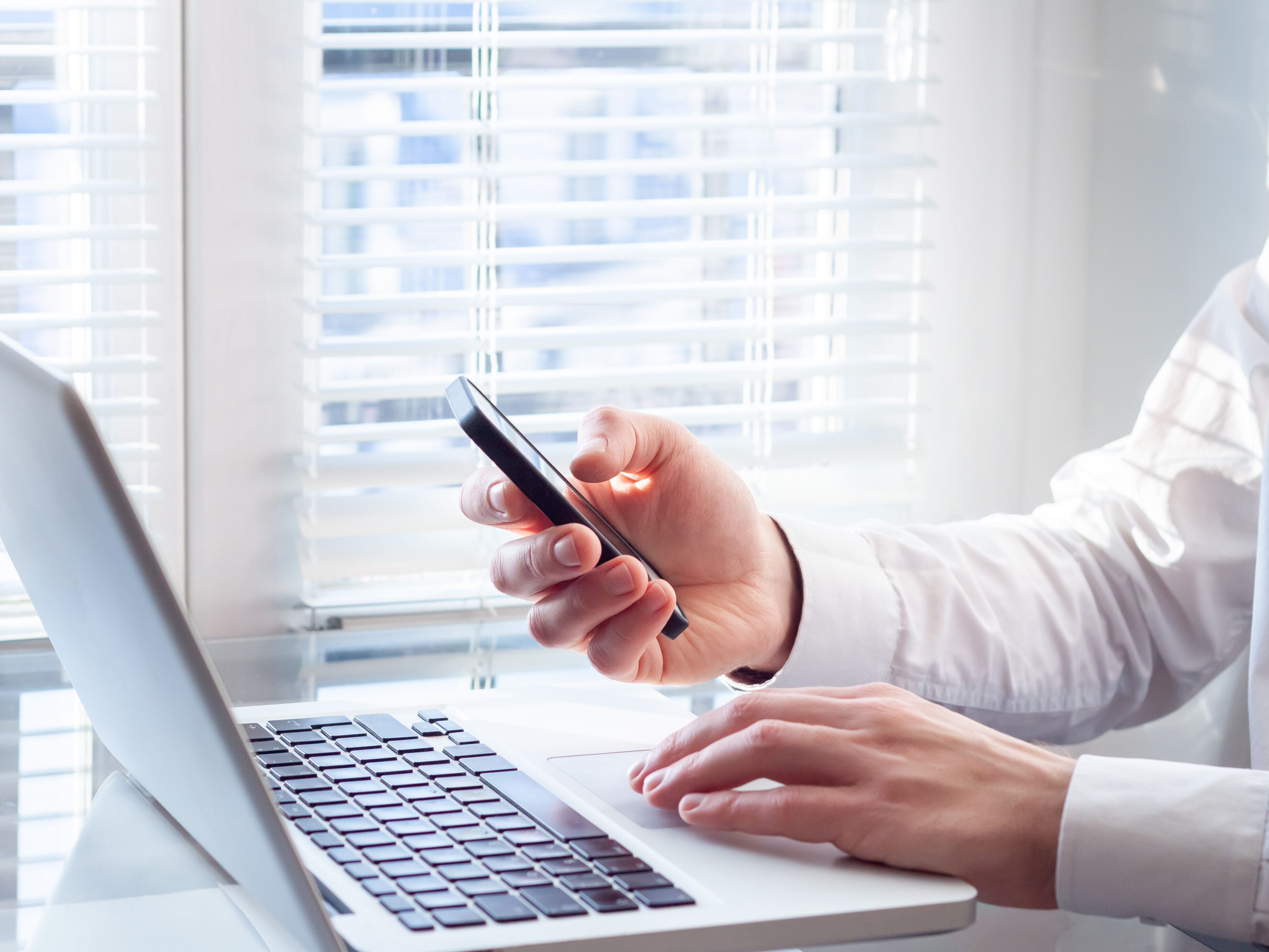 Businessman working with laptop and smartphone, bright office, f